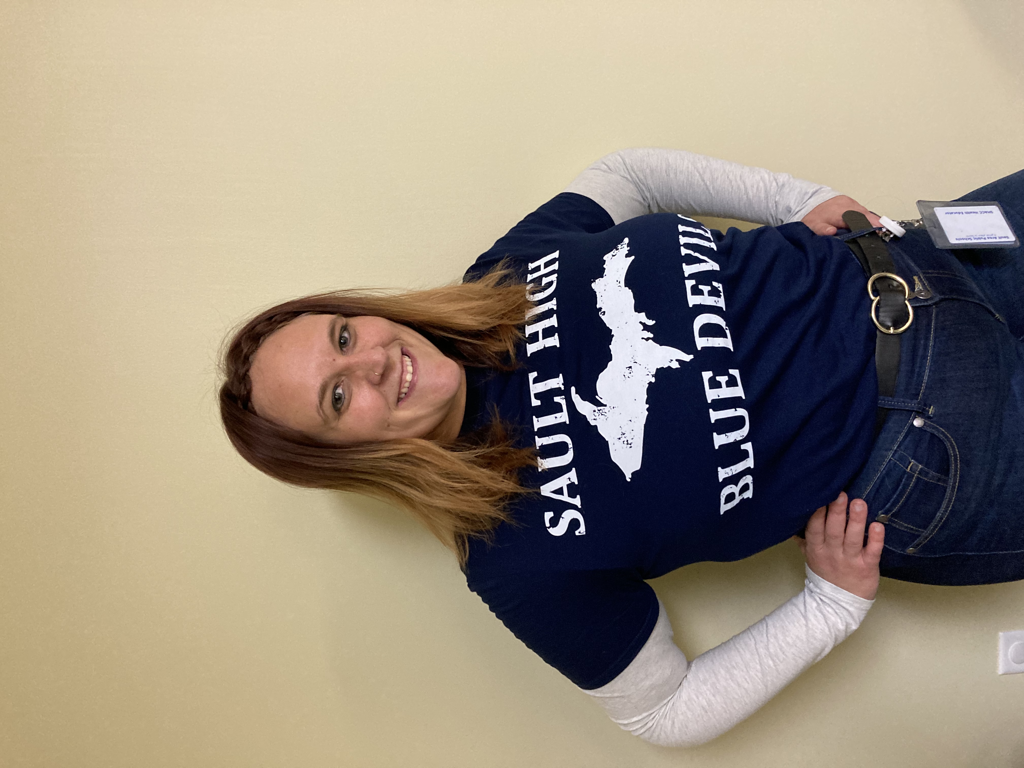 Woman with reddish-brown hair smiling at camera wearing a Sault High Blue Devils t-shirt.
